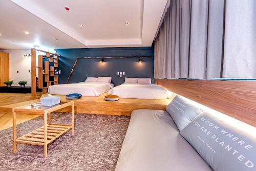 济州市The Jade Hotel的一间带两张床和一张沙发的卧室