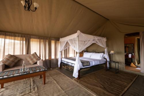 塞伦盖蒂Serengeti Woodlands Camp的一间帐篷内带天蓬床的卧室