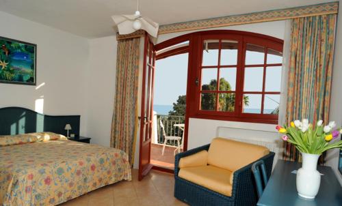 圣雷莫拉孔卡阿祖拉酒店的卧室配有床、椅子和窗户。