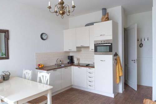 德里默伦De Dorsvloer的厨房配有白色橱柜和桌子
