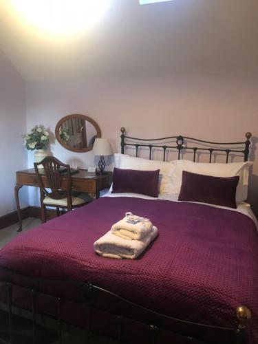 Ibstock波斯特豪斯酒店的一间卧室配有一张大床和紫色毯子