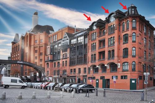 汉堡LOFT-Panoramablick-HAFEN & ELBE!的一座大型砖砌建筑,前面有汽车停放