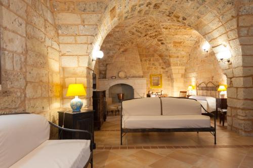 SternatiaAgriturismo Masseria Chicco Rizzo的石墙客房设有一间带三张床的卧室