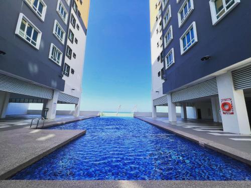瓜拉丁加奴Renai Homestay Ladang Tanjung Kuala Terengganu with POOL的两栋建筑之间的一个游泳池,两栋建筑之间有蓝色的水