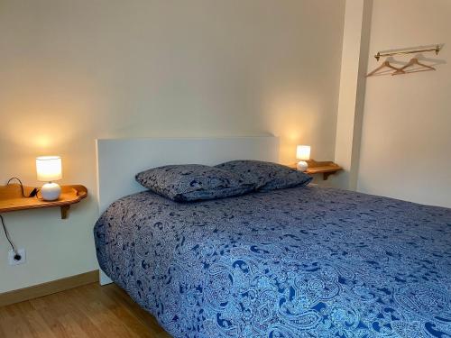 贝叶Le Mulberry的一间卧室配有一张带蓝色被子的床和两盏灯。