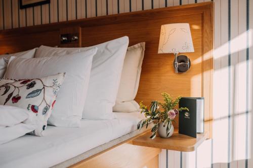 彻默岛Engø Gård Hotel & Restaurant的一间卧室配有带白色枕头和灯的床