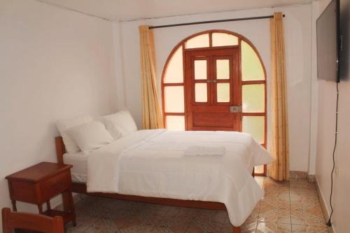 阿亚库乔MESONERO的卧室配有白色的床和拱形窗户