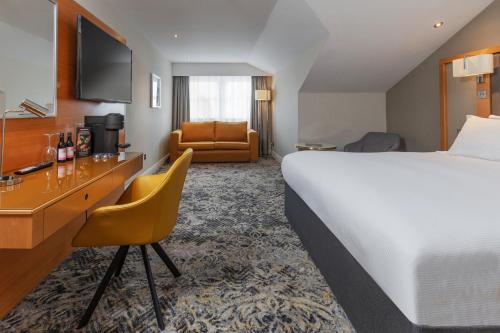 凯尼尔沃思Chesford Grange Hotel的酒店客房设有一张大床和一张书桌。