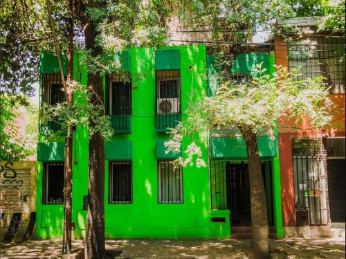 门多萨Clover Hostel的前面有树木的绿色建筑