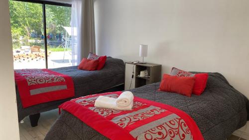 DoñihueHostal Doñihue的一间卧室配有两张红色和灰色的床