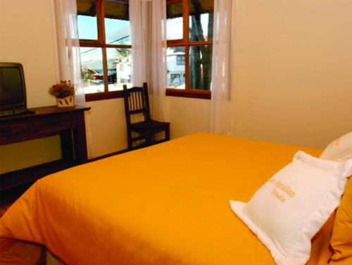 乌斯怀亚Cabañas Las Aguilas ADHERIDA PREVIAJE的一间卧室配有黄色的床和电视