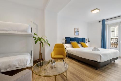 马拉加Malaga City Suites的一间卧室配有两张床、椅子和玻璃桌