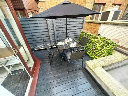 伦敦LUXURIOUS Terrace 2 Bedrooms in Relaxing Covent Garden Apartment的庭院配有遮阳伞和桌椅。