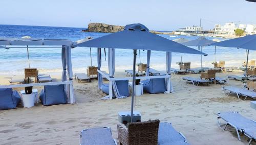 雷夫科斯卡尔帕索Le Grand Bleu Studios & Apartments的海滩上摆放着蓝色的桌椅和遮阳伞
