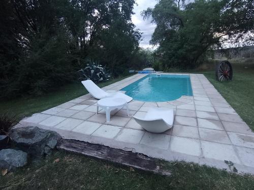 且乌塔Casita campestre的一个带两把白色椅子的游泳池和一个游泳池