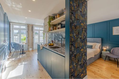 波尔图As Vizinhas Boutique Apartments的一间带蓝色橱柜的厨房和一间带一张床的客厅
