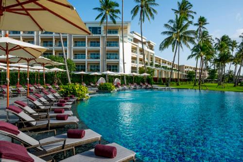 攀瓦海滩Phuket Panwa Beachfront Resort的酒店设有带椅子和遮阳伞的游泳池