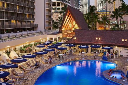 檀香山OUTRIGGER Reef Waikiki Beach Resort的一张酒店游泳池的图片,里面摆放着椅子和遮阳伞