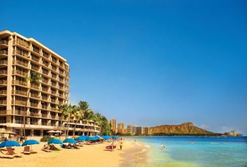 檀香山OUTRIGGER Reef Waikiki Beach Resort的沙滩上,有遮阳伞和人