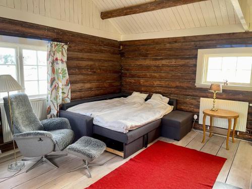 法尔雪平Backgårdens Timmerstuga的一间卧室配有一张床、一把椅子和红色地毯