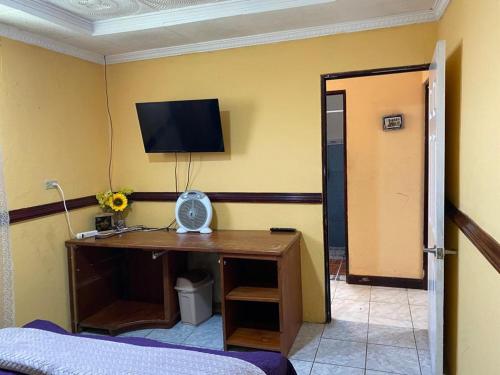 阿拉胡埃拉Casa Lupita Alajuela的一间设有一张桌子的房间,墙上有一台电视机
