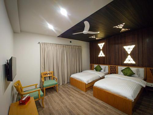 奎达Grand Hotel Quetta的一间卧室配有两张床、一张桌子和一把椅子