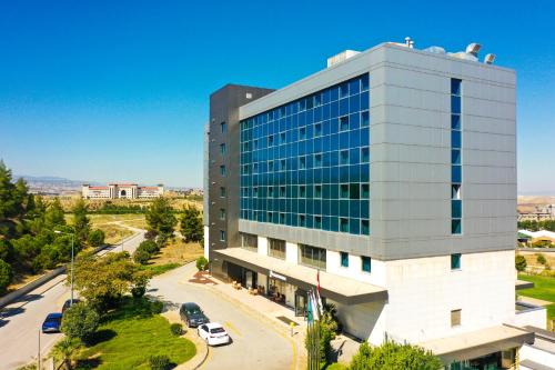 代尼兹利Park Dedeman Denizli的一座高大的玻璃建筑,设有停车场