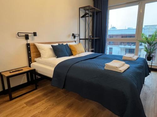 克拉科夫PM. Apartments Krakow的一间卧室配有一张带蓝色床单的床和一扇窗户。