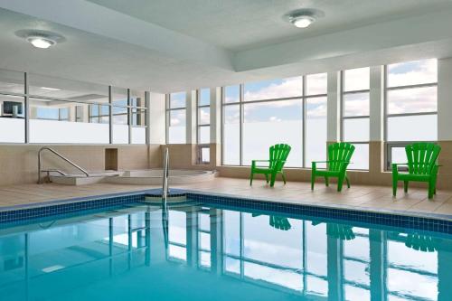 尼亚加拉瀑布尼亚加拉大瀑布景观温德姆酒店的一个带两把绿色椅子和浴缸的游泳池