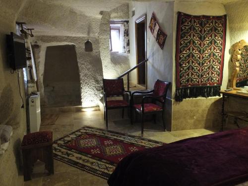 格雷梅Anatolia cave hotel Pension的一间卧室配有一张床、两把椅子和电视