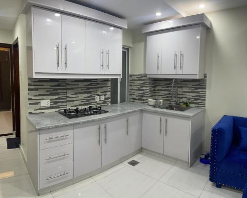 JhelumPremier Heights Jhelum的厨房配有白色橱柜和蓝色椅子