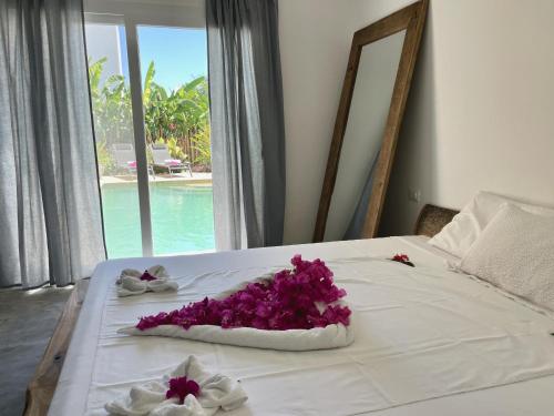 吉汶瓦Tangawizi Villa with Private Pool ZanzibarHouses的一张床上有一大束紫色花