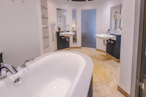 纽伦堡罗特讷招待所罗曼蒂克酒店的浴室配有两个盥洗盆和浴缸。