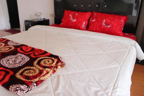 LagubotiHW. Hubers Hotel, Bar & Resto的一张白色的床,上面有红色枕头