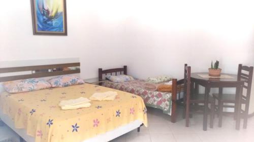 阿蒂巴亚Pousada Montanha da Pedra Grande的卧室配有两张床、一张桌子和一张桌子以及椅子。