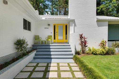 盖恩斯维尔UF SUNSHINE HOUSE - Patio & BBQ & Fire Pit - Chef Kitchen - Upscale Neighborhood!的白色的房子,设有黄色的门和楼梯