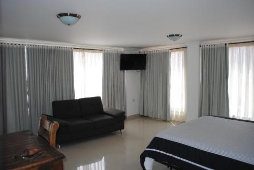 潘普洛纳COLOMBIA-Hotel Hontibon的一间卧室配有一张床、一把椅子和电视