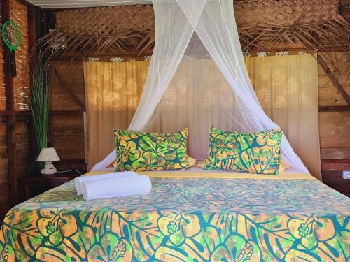 MahevaMoanaiti Lodge的一间卧室配有一张带天蓬和枕头的床
