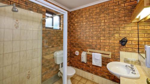 奥尔伯里The Cottage Motor Inn Albury CBD的一间带白色水槽和砖墙的浴室