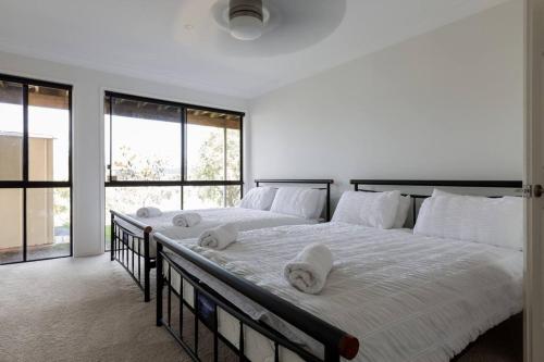 黄金海岸Gold Coast Theme Parks With a Pool的卧室配有一张带白色床单和窗户的大床。
