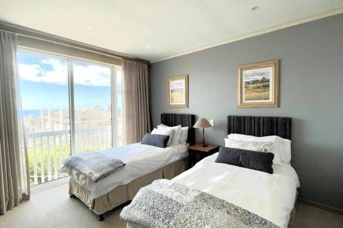DʼAlmeidaLuxury at Pinnacle Point - 3 Bedroom Villa的一间卧室设有两张床和大窗户