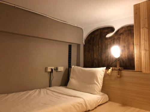 台北Hostel of Rising Sun 昇行旅的一间卧室配有一张床,墙上有灯