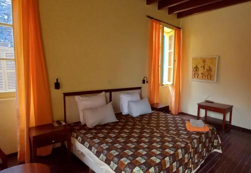格雷岛La Maison du Marin的一间卧室配有床和橙色窗帘的窗户