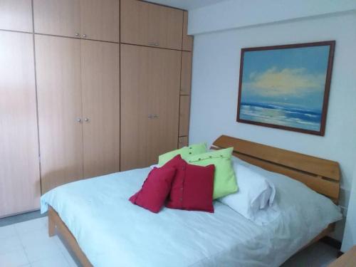 拉瓜伊拉Acogedor apartamento con piscina - Bleu Marine Suites的卧室配有白色的床和红色及绿色枕头