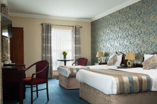 班多伦Holyrood Hotel - Leisure Centre & The Spa at Orchids的酒店客房配有两张床和一张书桌