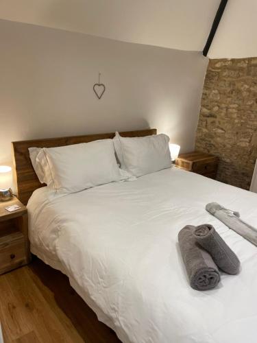 沃顿安德埃奇Cotswold Coombe Cottage的卧室配有白色床和毛巾