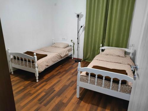 巴尔BONACA - BAR的配有绿色窗帘和木地板的客房内的两张床