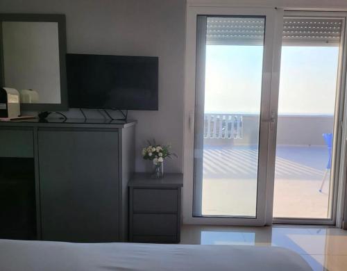 卡萨米尔Vila Chelsea的一间卧室配有一张床、一台电视和一个阳台