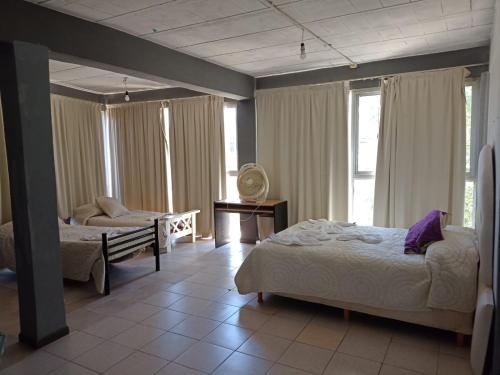 米娜克拉韦罗Complejo Navi的一间卧室设有两张床、一把椅子和窗户。