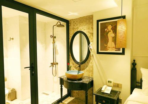 河内Hanoi Emerald Waters Hotel Valley的浴室配有盥洗盆和带镜子的淋浴